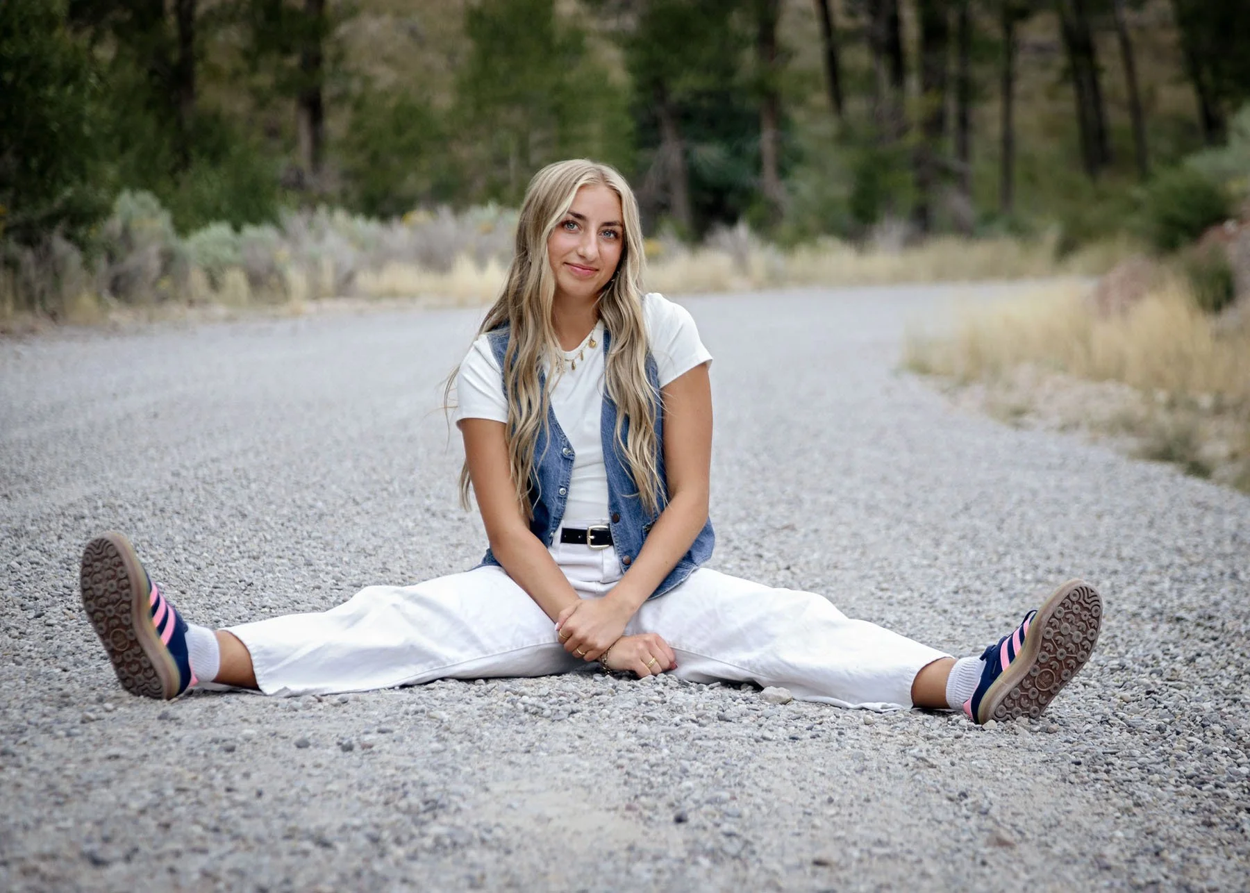 Three senior girls posing on dirt road in mountains wearing white pants
