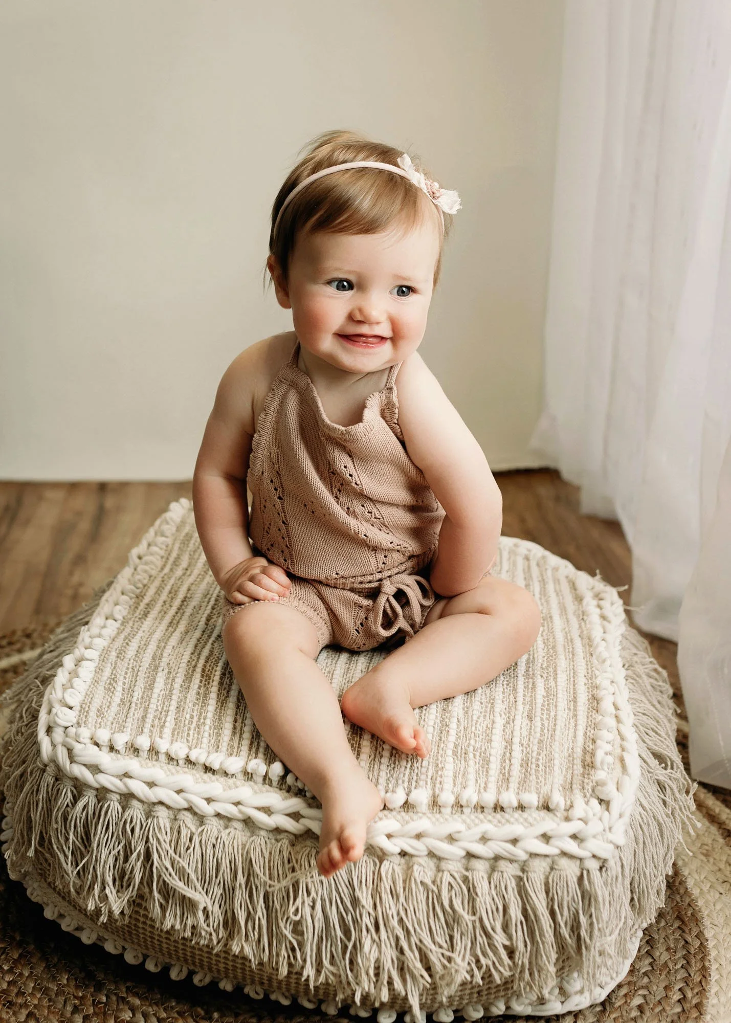 Baby sitting in front of bed on rustic chair during session