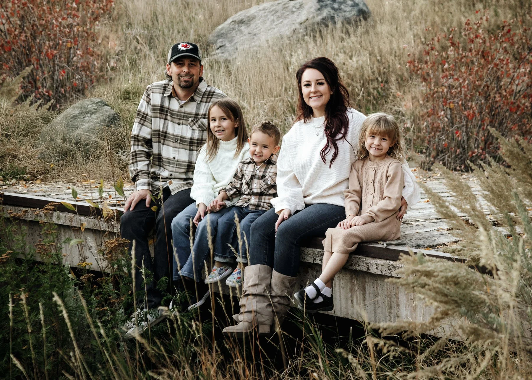 Family standing on wooden bridge with rocks and greenery