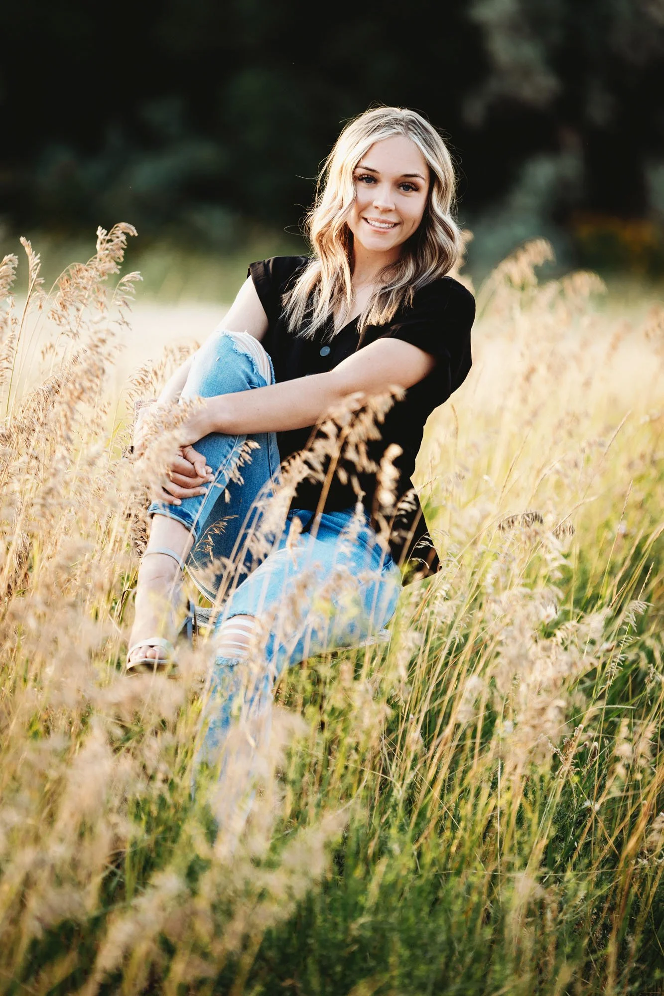 Teen girl sitting on chair hugging herself in tall grass