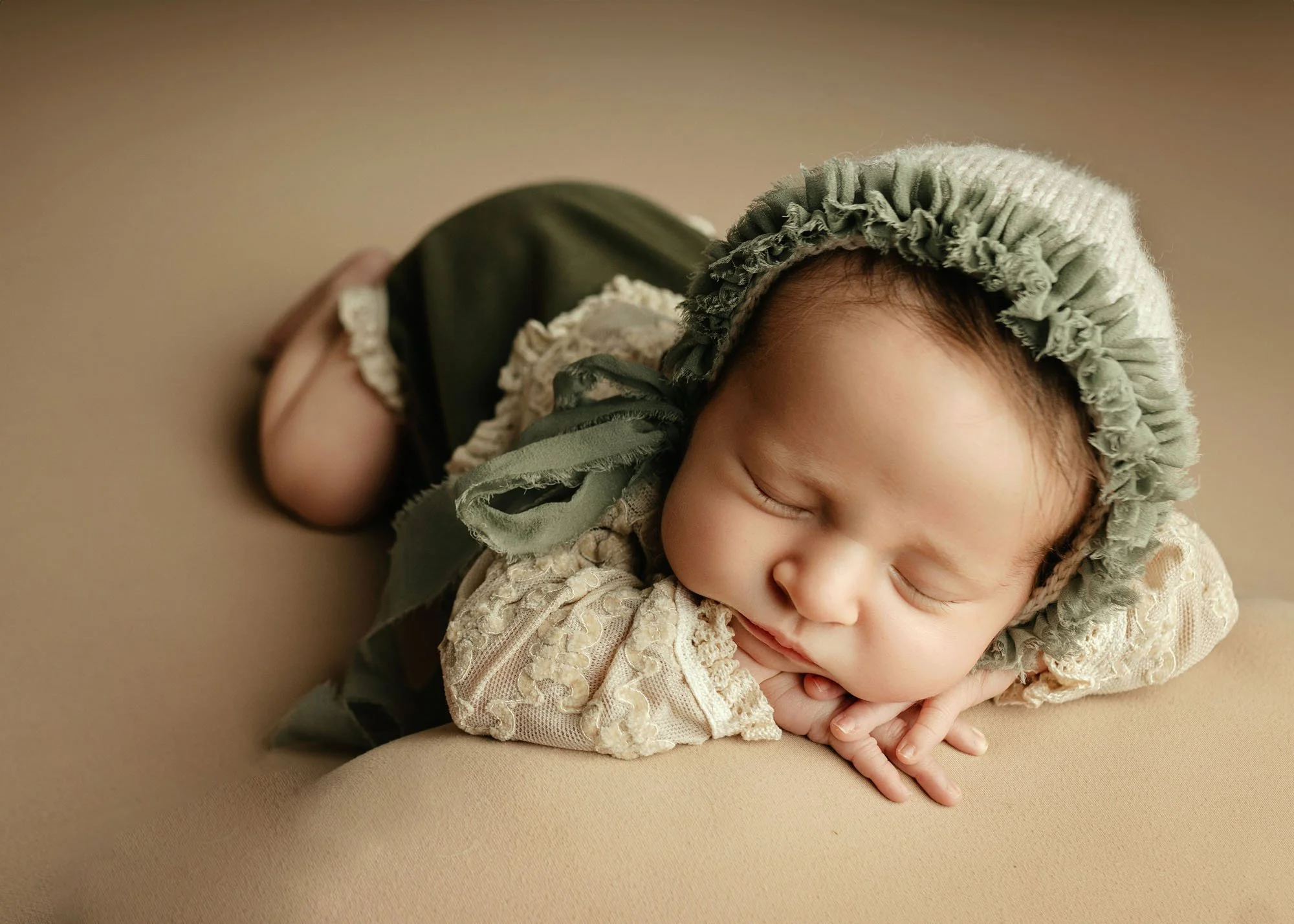 head on hands baby sleeping in green outfit