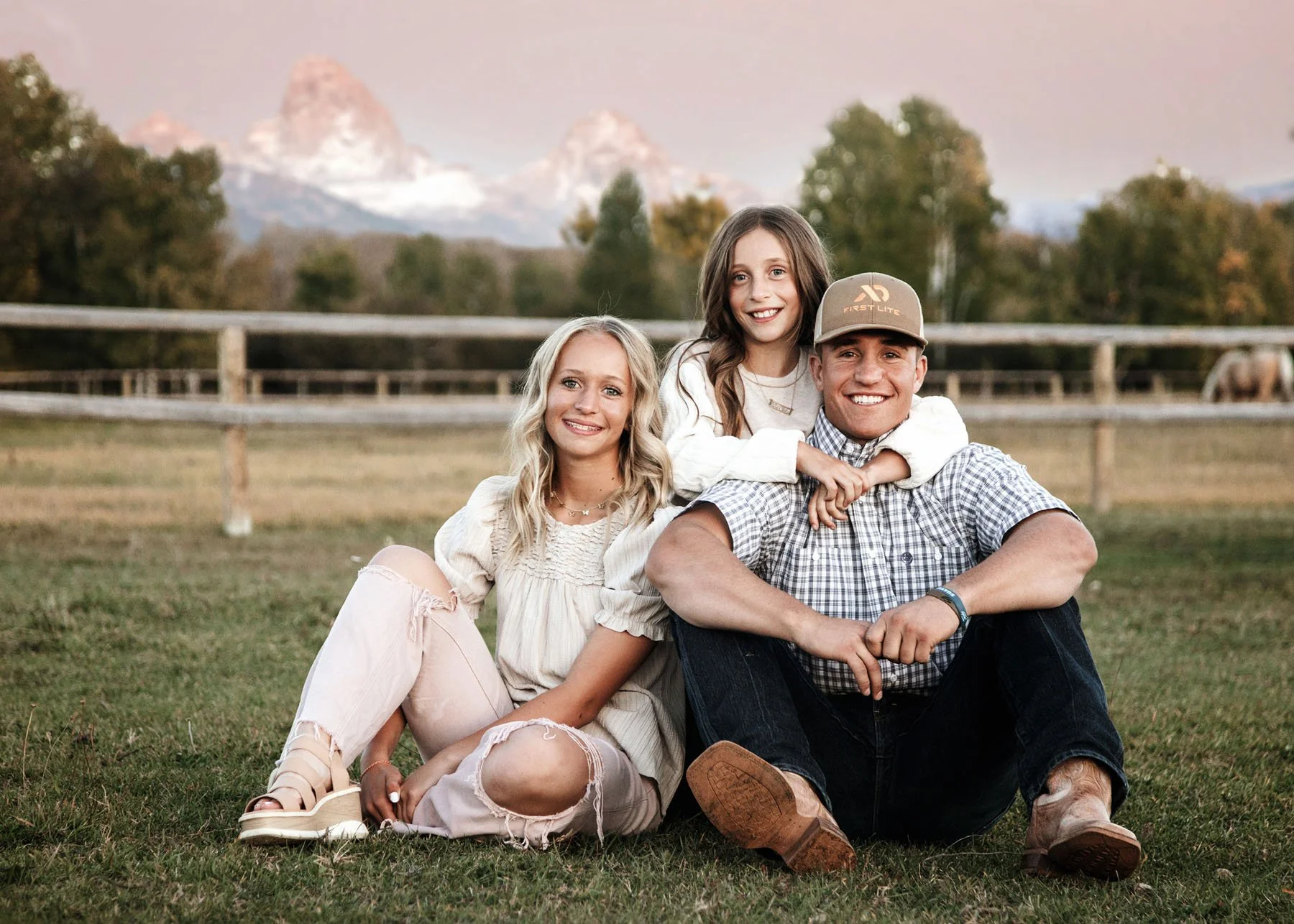 Parents and children standing by fences with mountains and horses