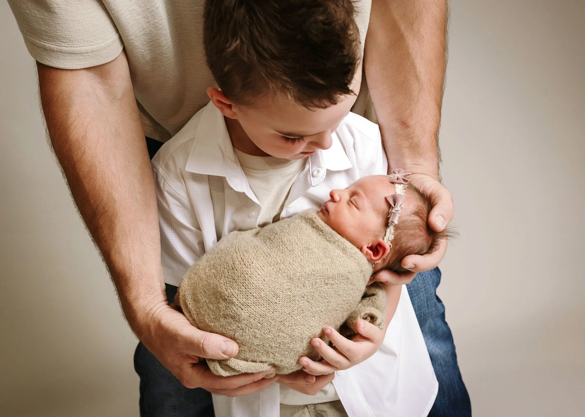 big brother holding newborn with daddy help