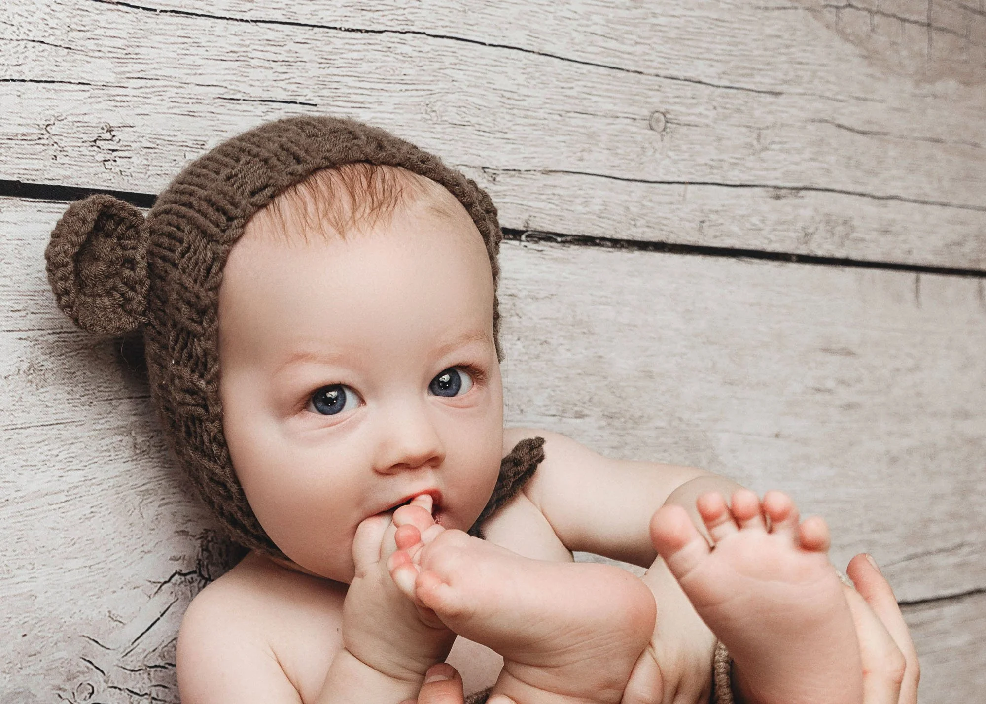 Baby milestone session eating toes with playful expression