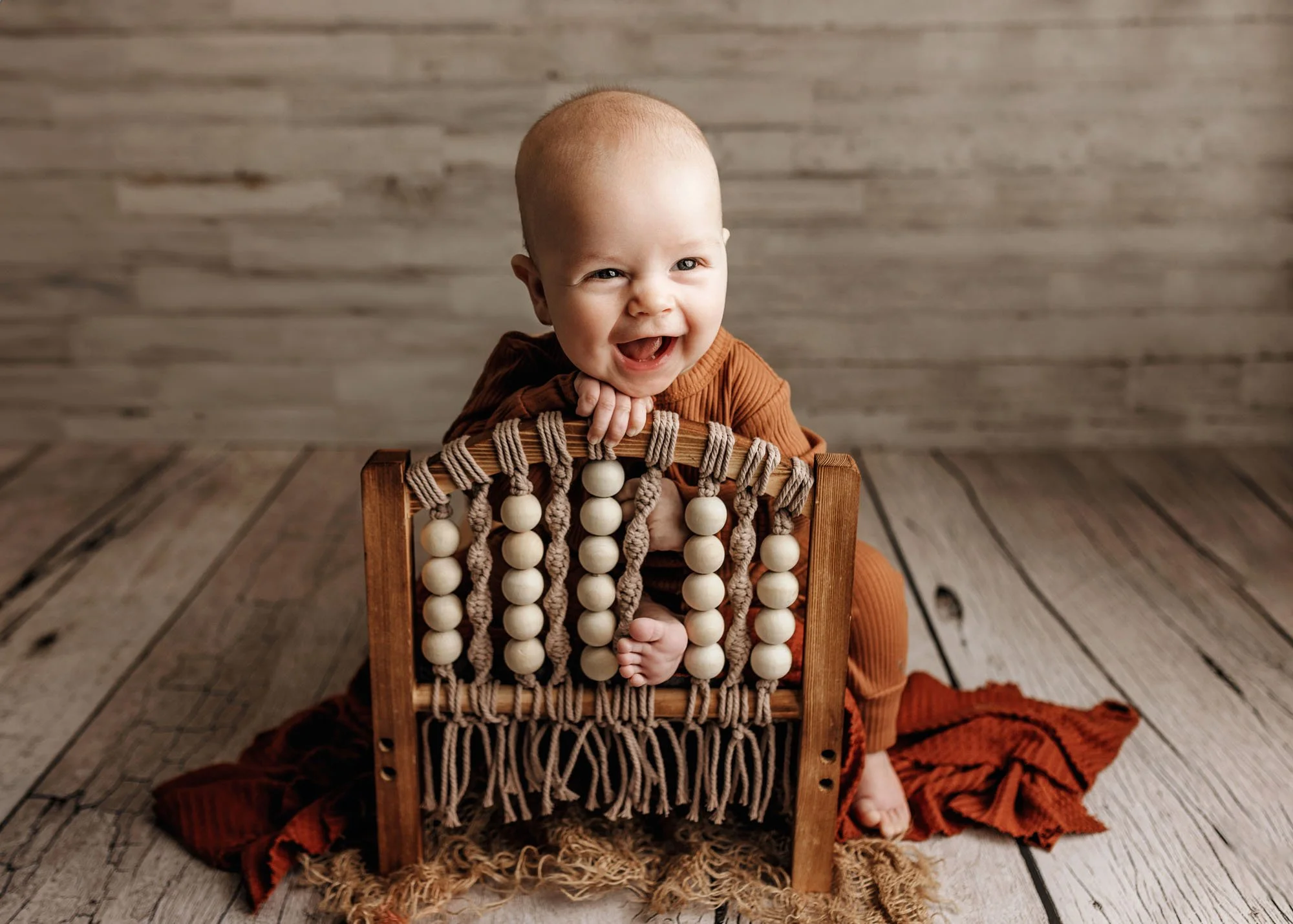 Baby sitting in child-size bed during milestone session