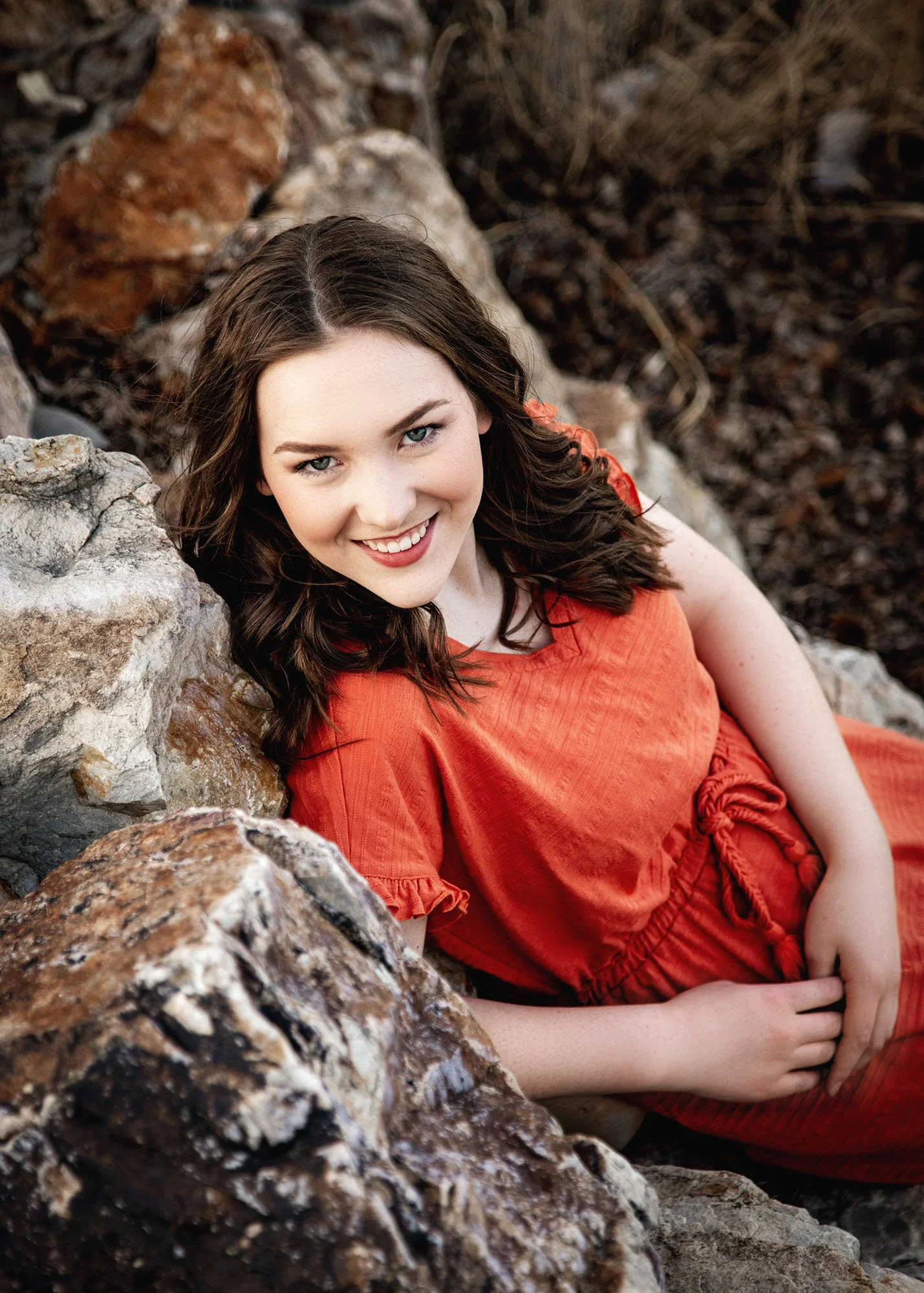 Senior girl laying on tummy on rocks for outdoor portrait