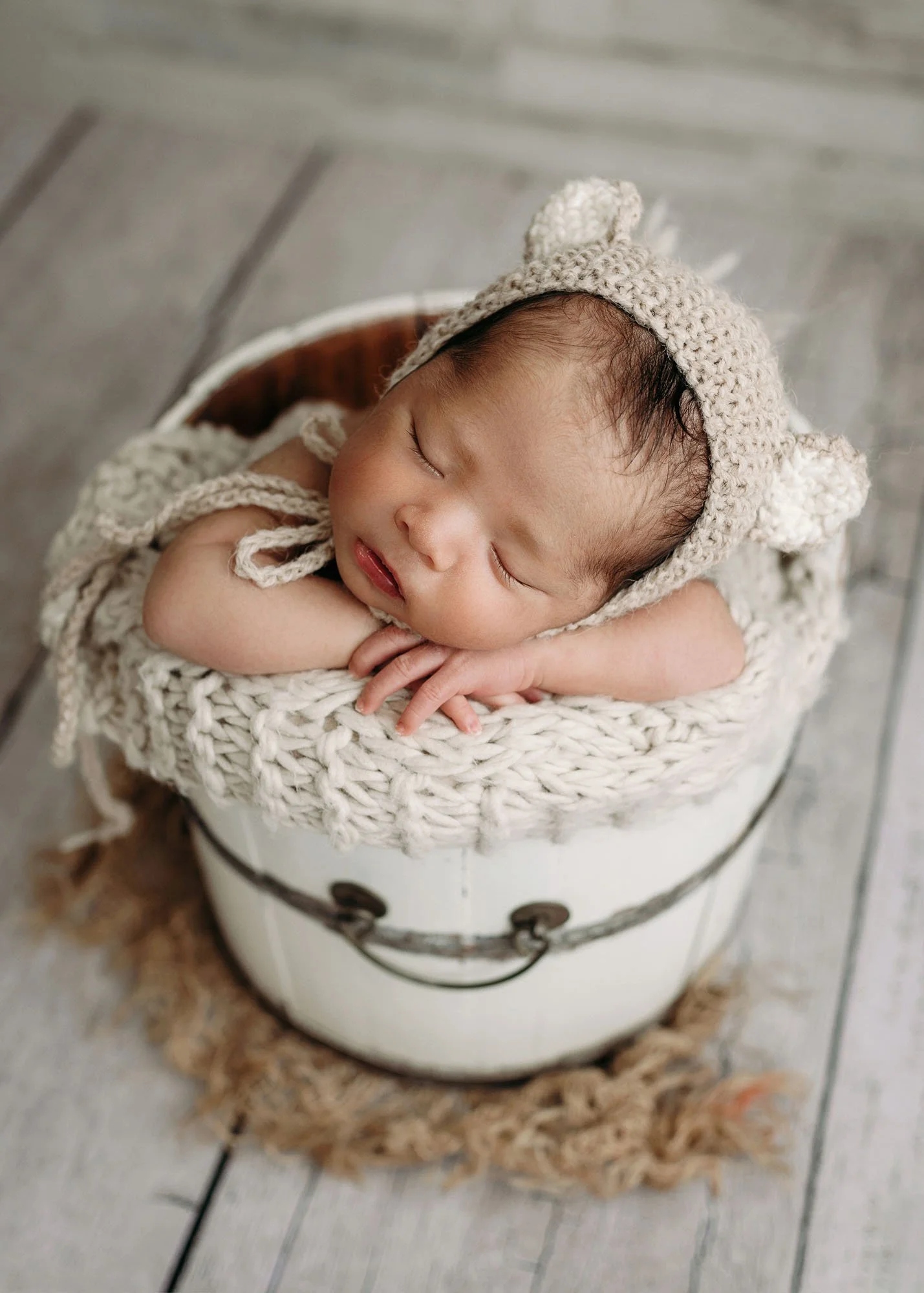 Newborn posed in bucket with head and hands resting over the edge