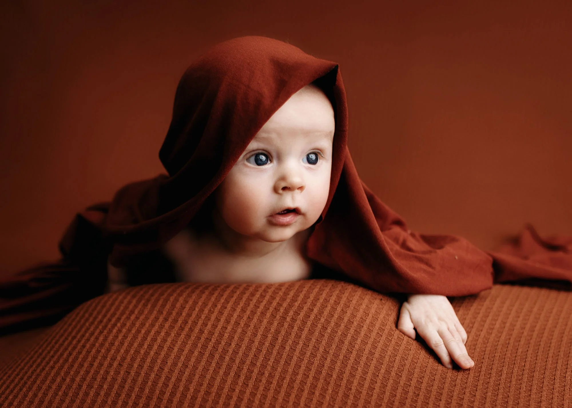 Baby on tummy with joyful expression in studio session