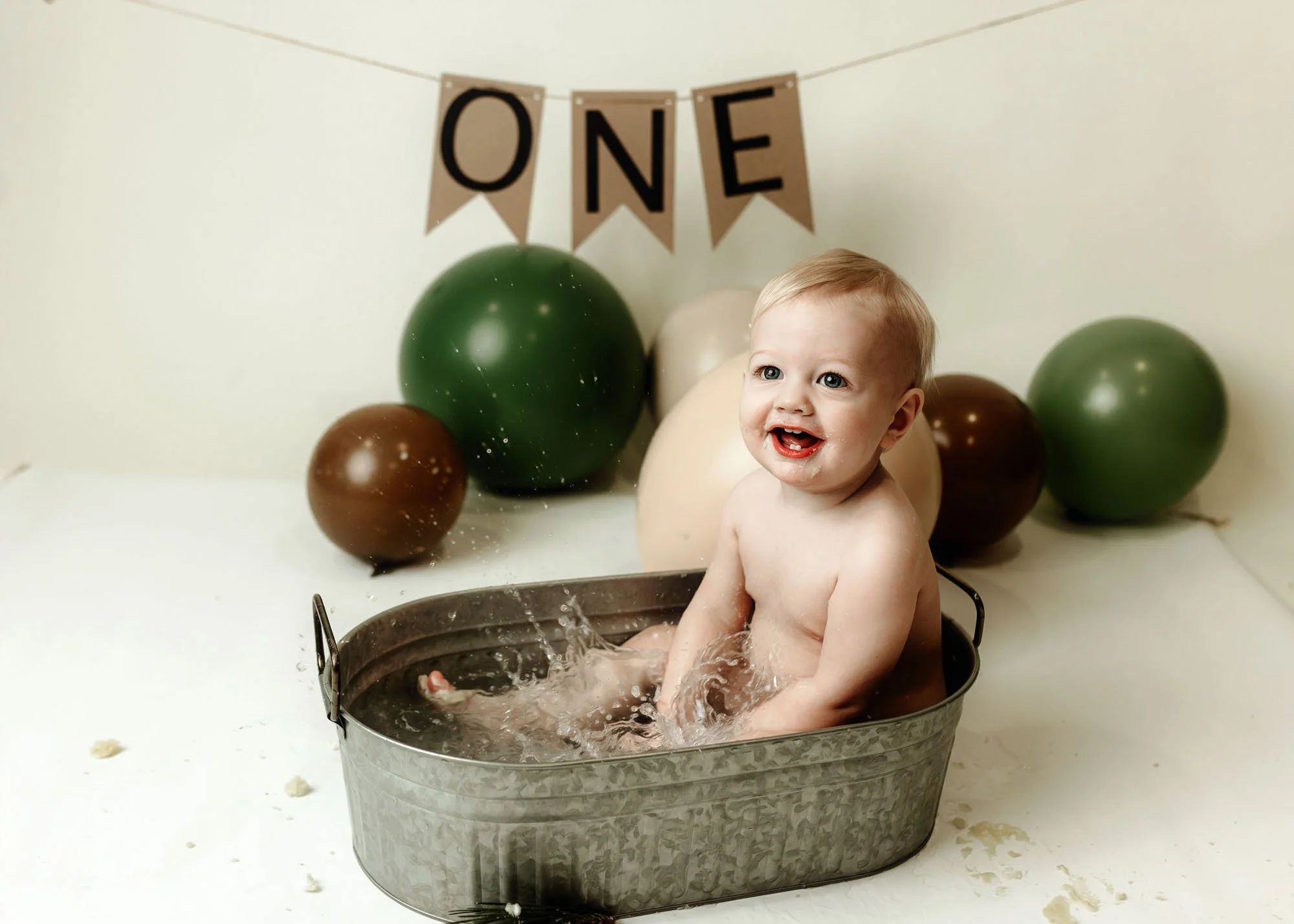 One year old boy in neutral cake smash session with green decor