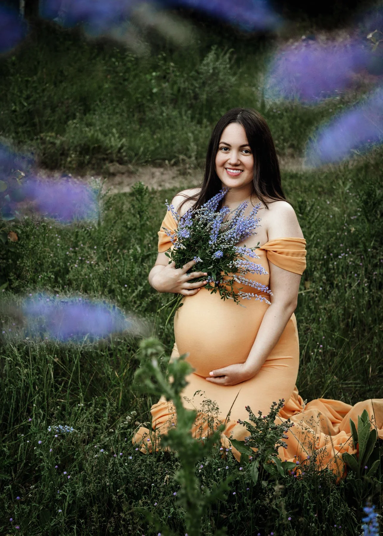 Mama in yellow dress sitting in lavender field holding baby bump