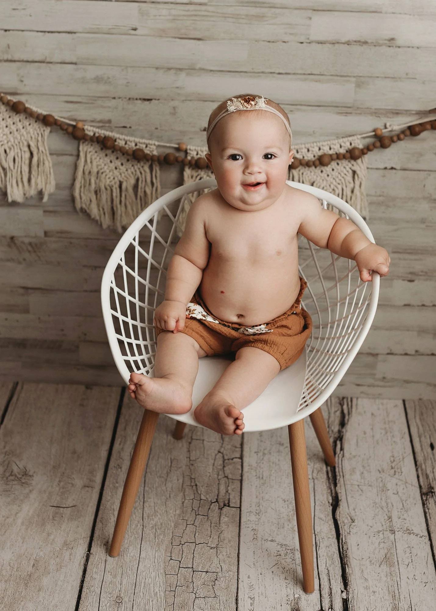 Baby sitting on white chair with white studio background