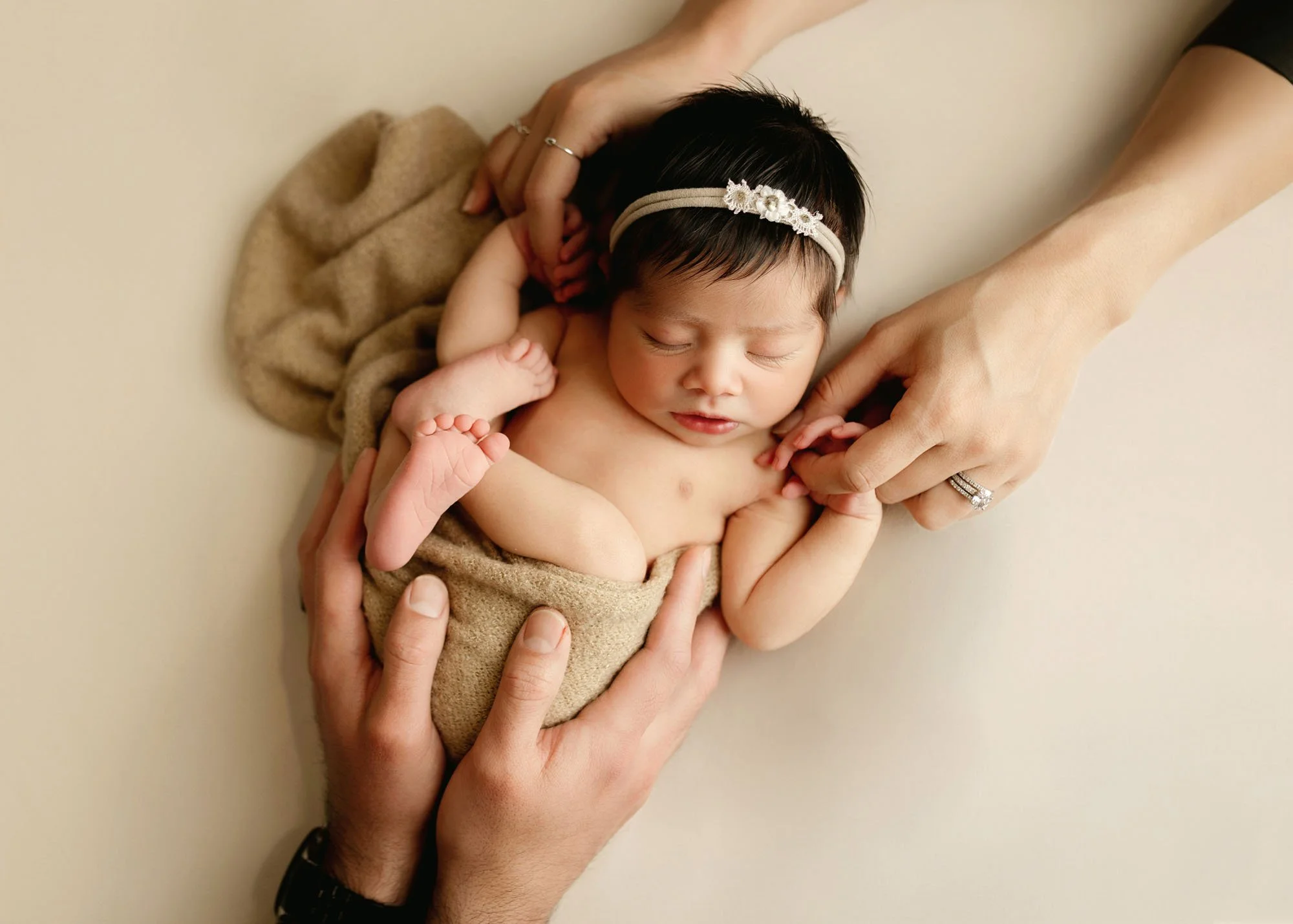 family hands on baby in tuck fin pose