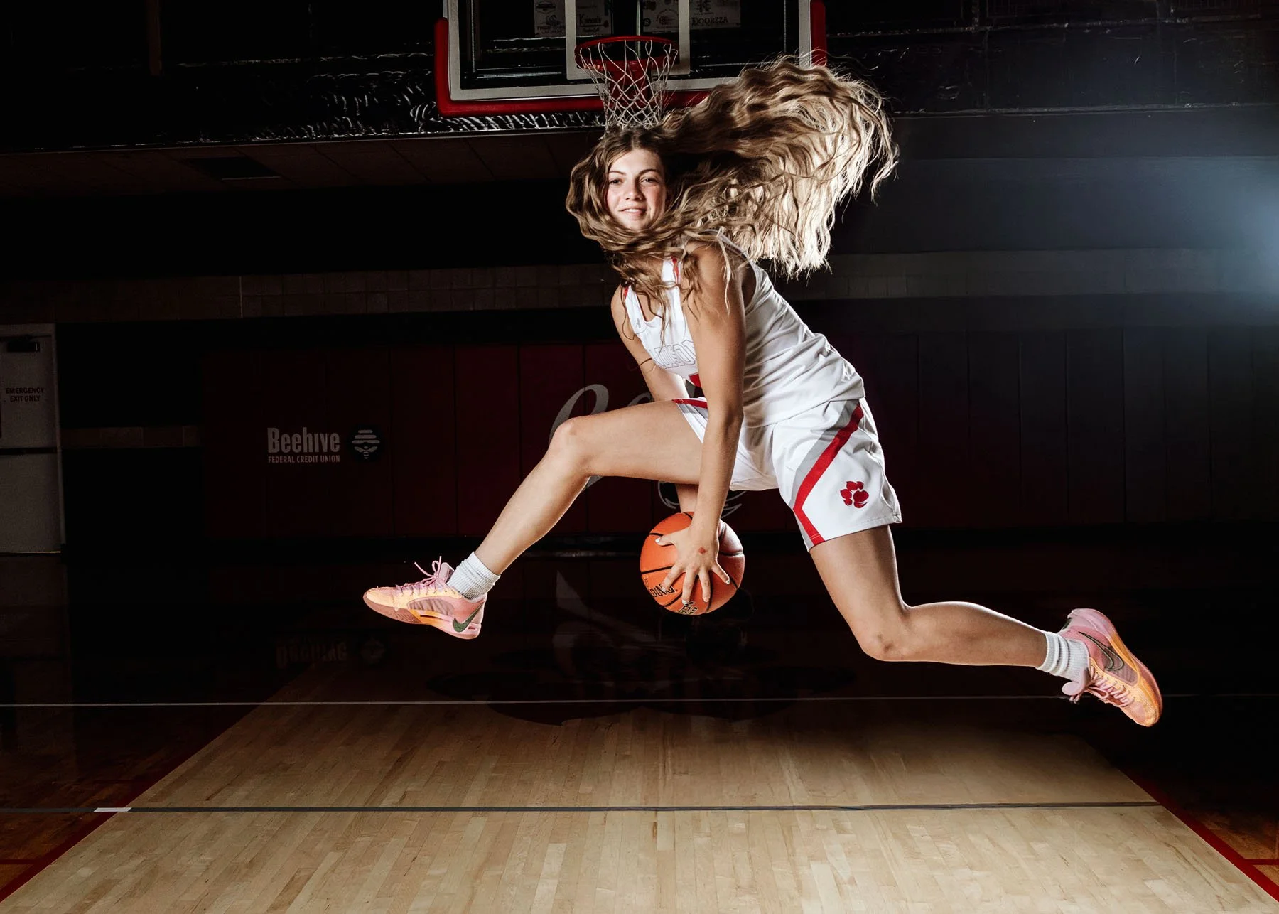 Senior girl jumping with basketball for outdoor senior portrait