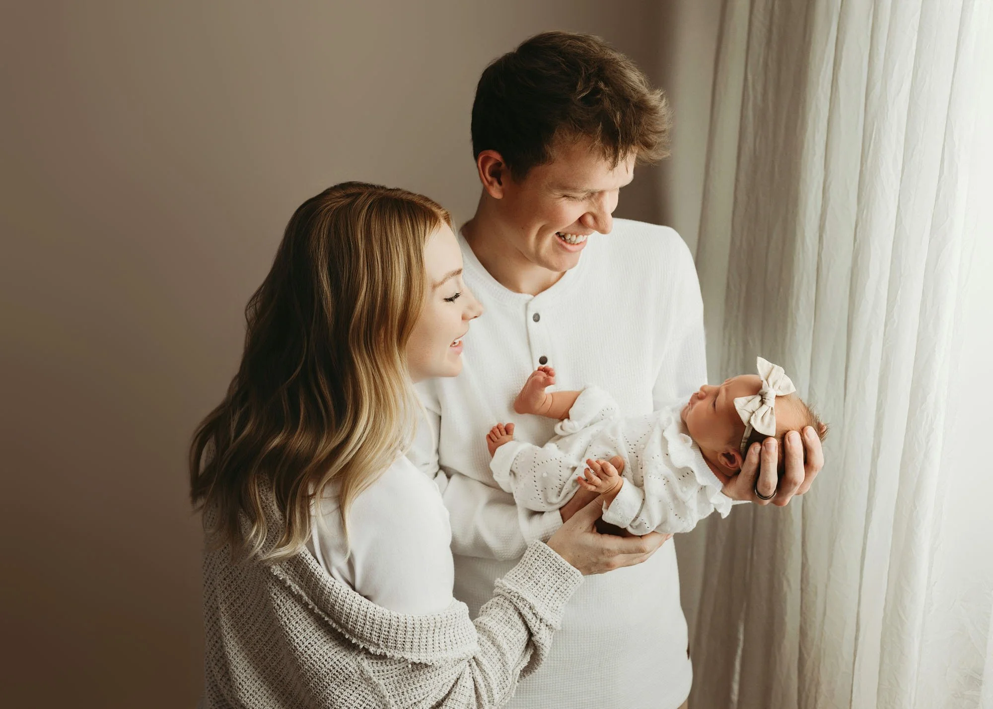 Family cuddling newborn on bed during Idaho Falls newborn photography session