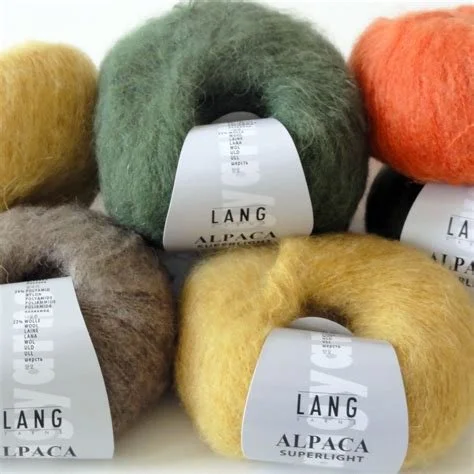 Bunte Wollknäuel in verschiedenen Farben, inklusive grün, gelb, orange, grau und braun, mit Labels, die 'LANG ALPACA' und 'SUPERLIGHT' tragen.