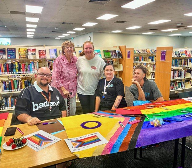 Community Members sitting in front of Progress Flag artwork