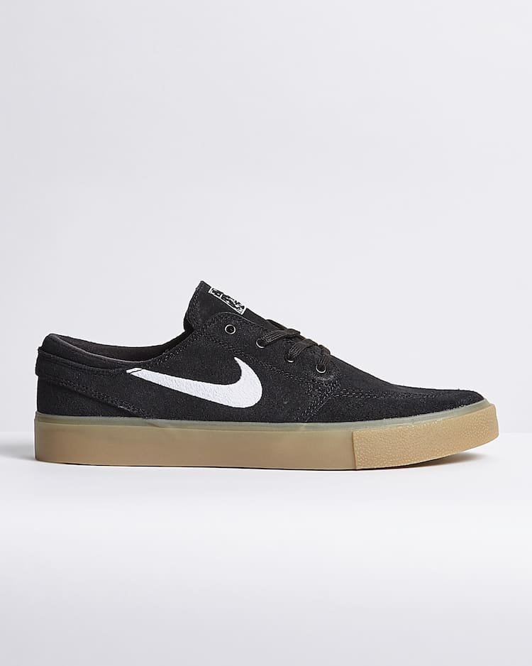 Black Nike sneaker with white swoosh and gum sole on grey background.