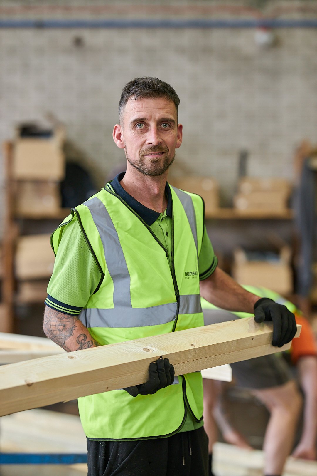 Construction worker in a high-visibility vest holding a piece of wood
