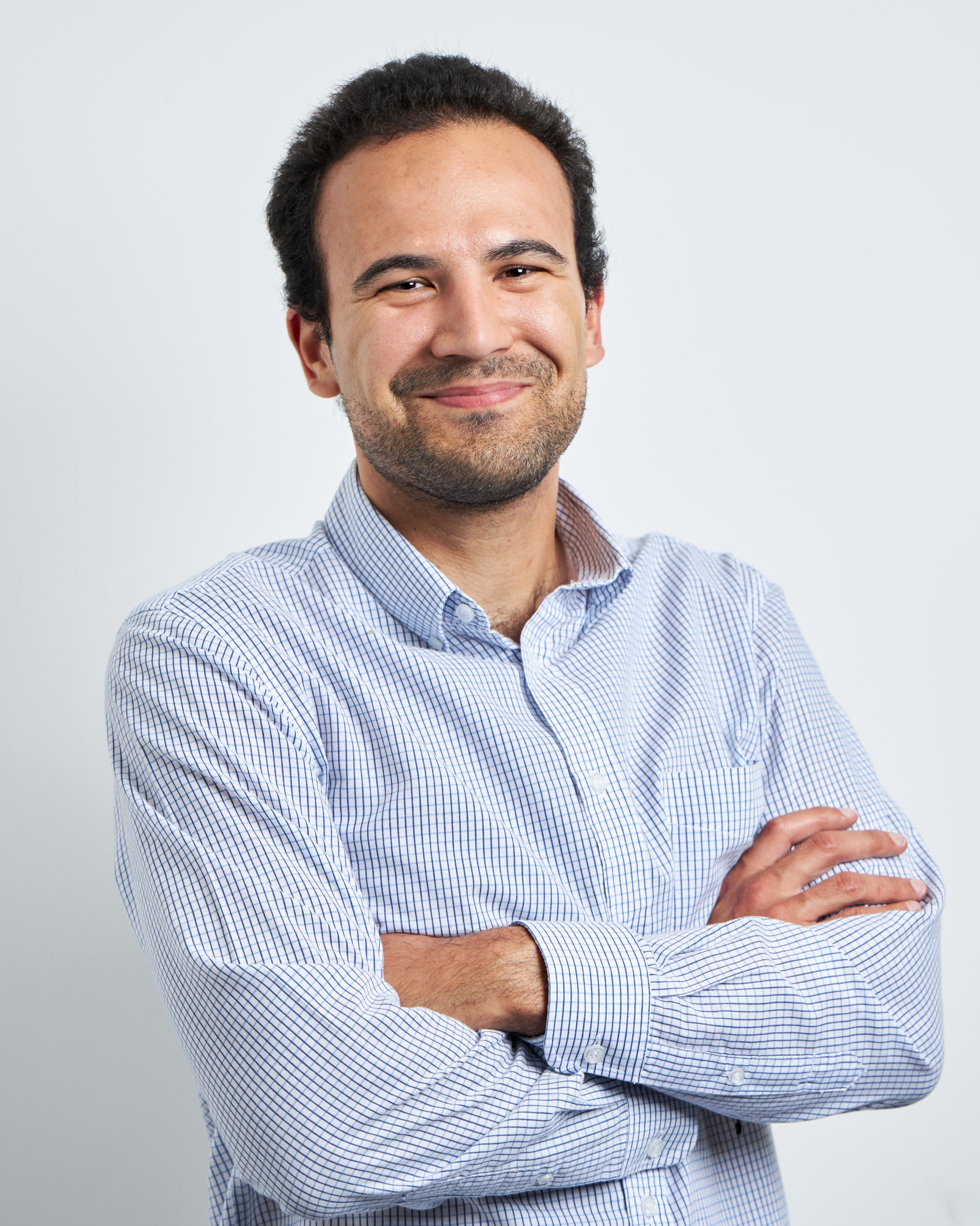 Smiling person in checked shirt with arms crossed