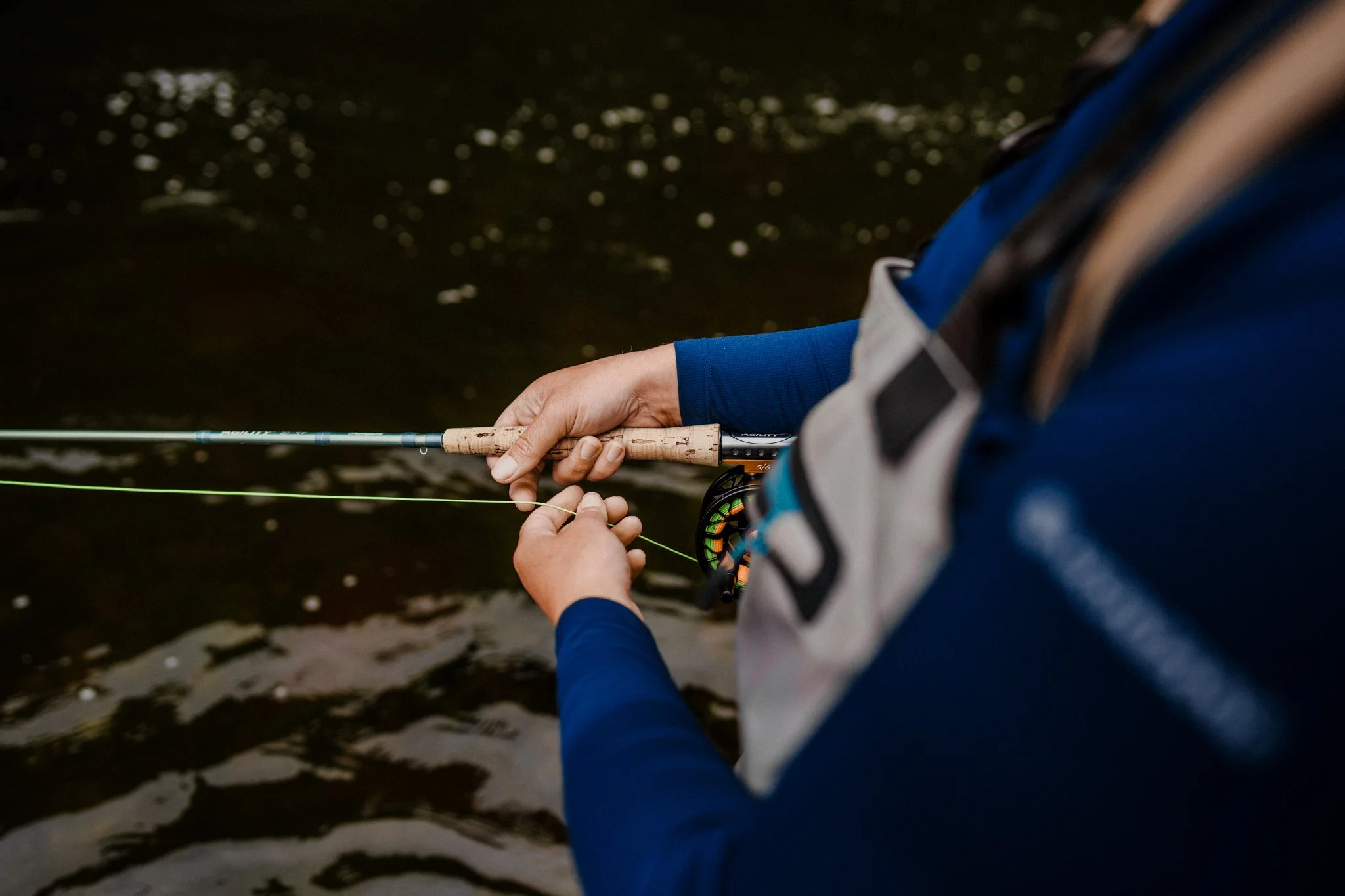 Freelance Lifestyle Photographer A person fishing in a dark body of water, holding a fishing rod with both hands.