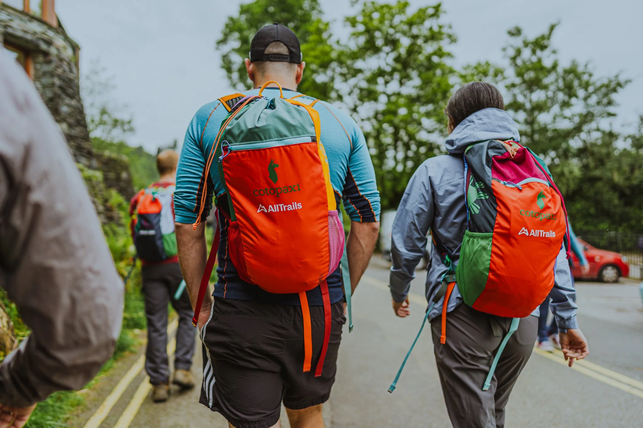 Freelance outdoor Lifestyle Photographer A group of hikers walking on a trail with trees, wearing colorful backpacks.
