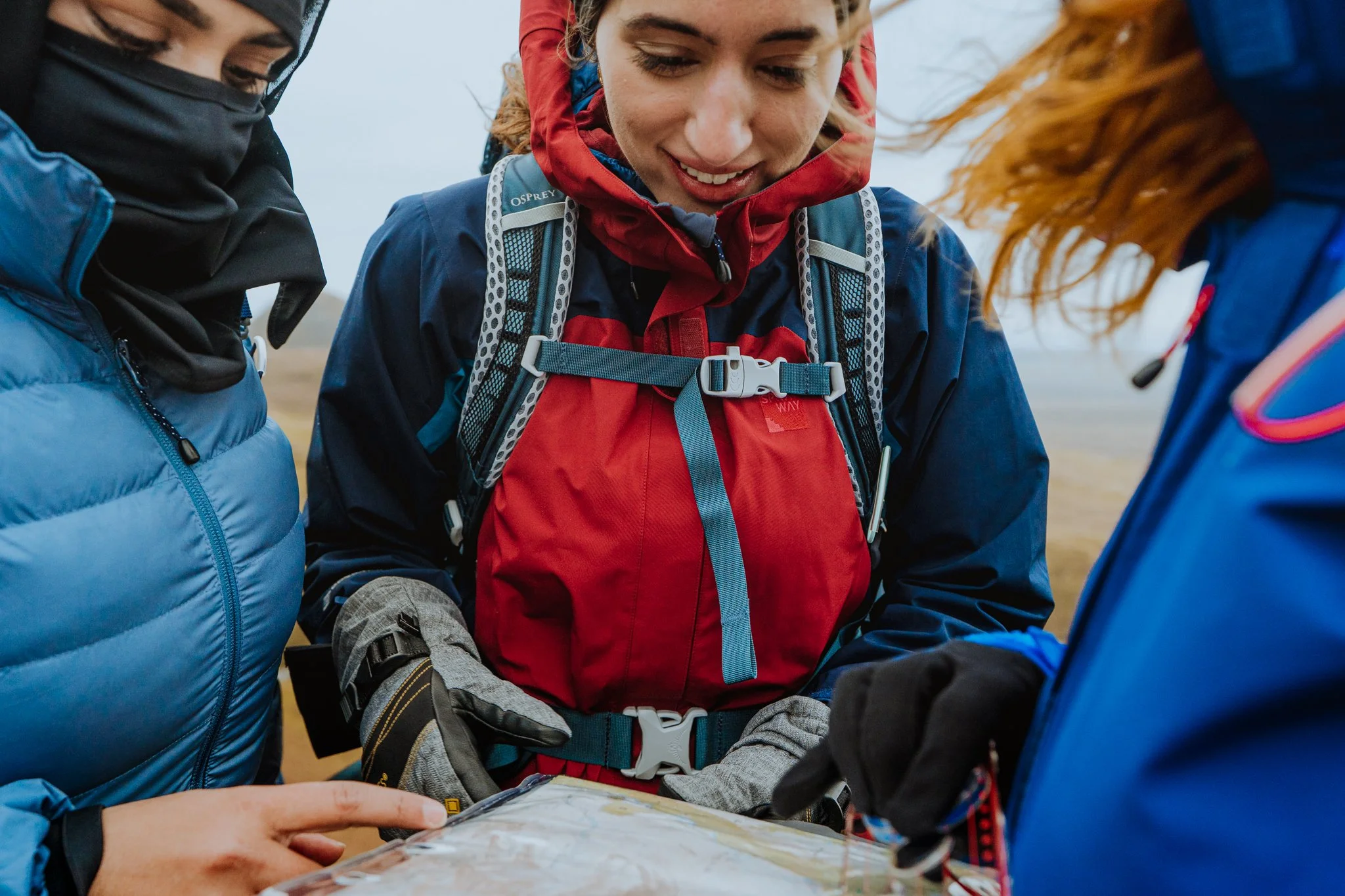Freelance Lifestyle Photographer Three women dressed in outdoor winter gear looking at a map outdoors.