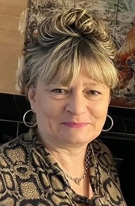 Woman with patterned blouse and hoop earrings smiling
