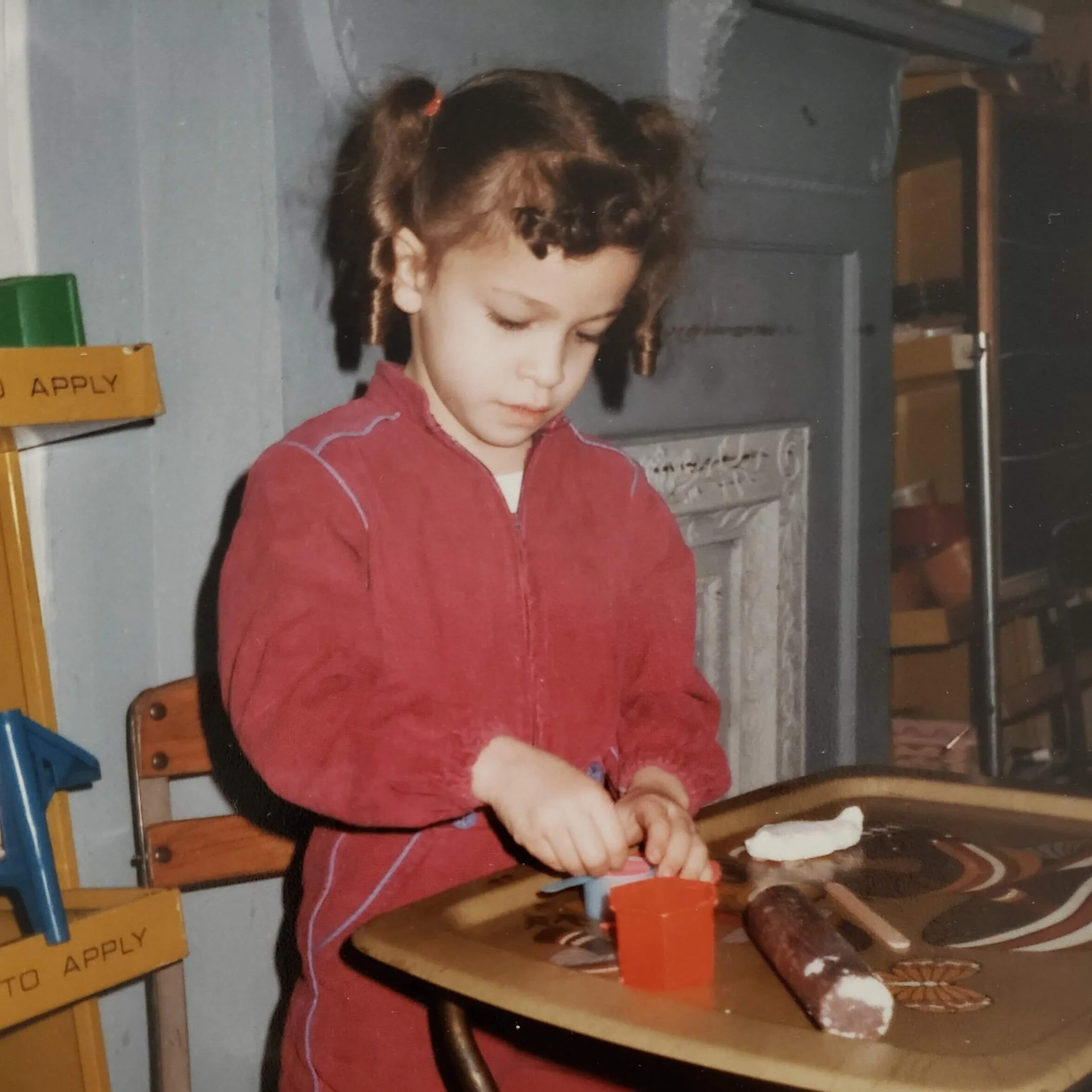 Childhood photo of artist Ava Bock at age five creating clay art in a school studio, reflecting early material exploration and the roots of her sustainable art practice.