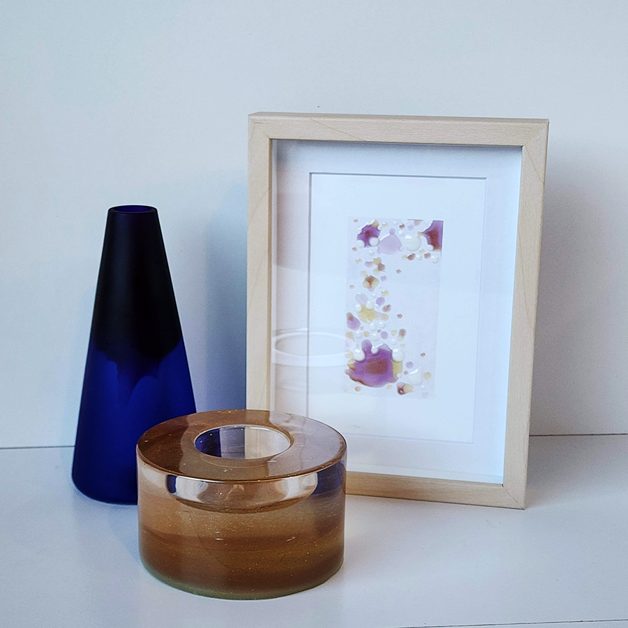 Grouping of three bioresin works by artist Ava Bock—a cobalt vase, amber candle holder, and framed abstract painting—representing renewal and handcrafted artistry.