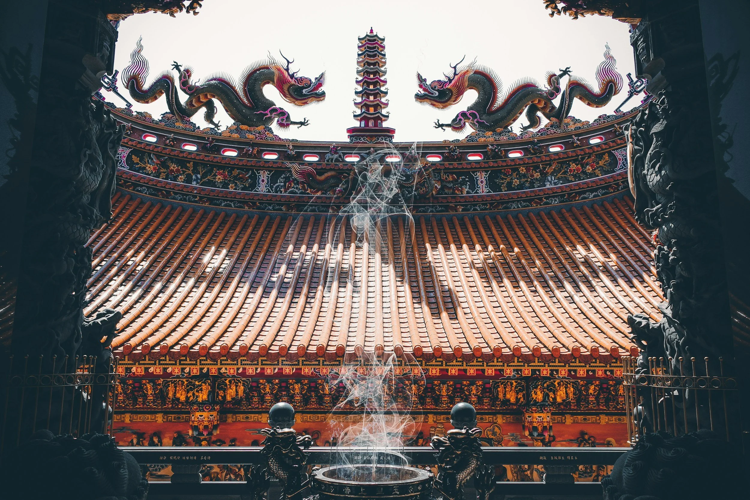 Interior view of a traditional Chinese temple with ornate dragons and a pagoda, viewed through an open doorway with smoke rising from a ritual incense burner.