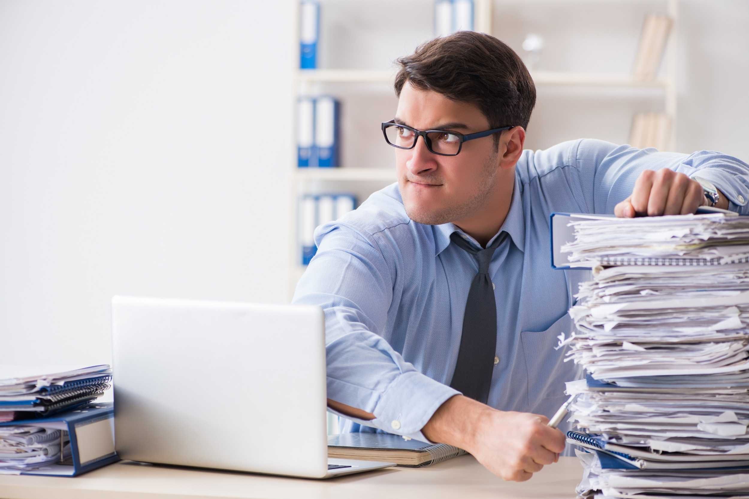 A HR Manager has piles of paperwork in front of him
