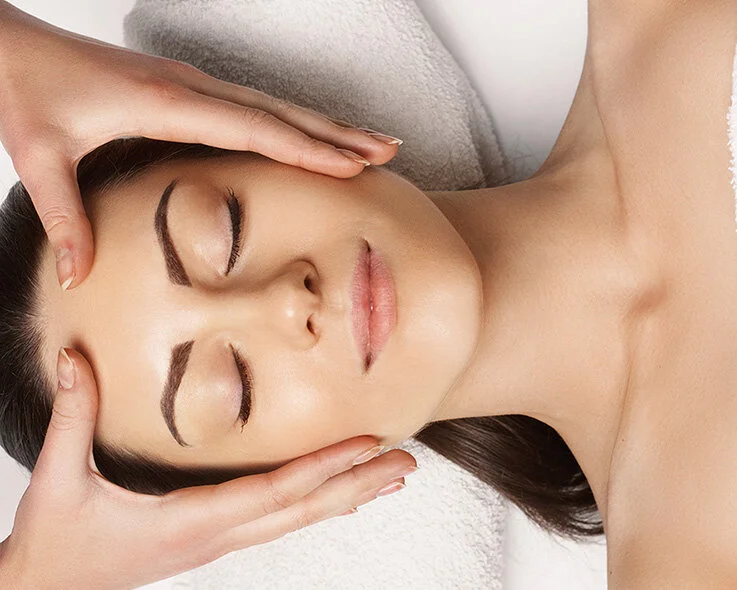 Young woman with eyes closed getting a face massage