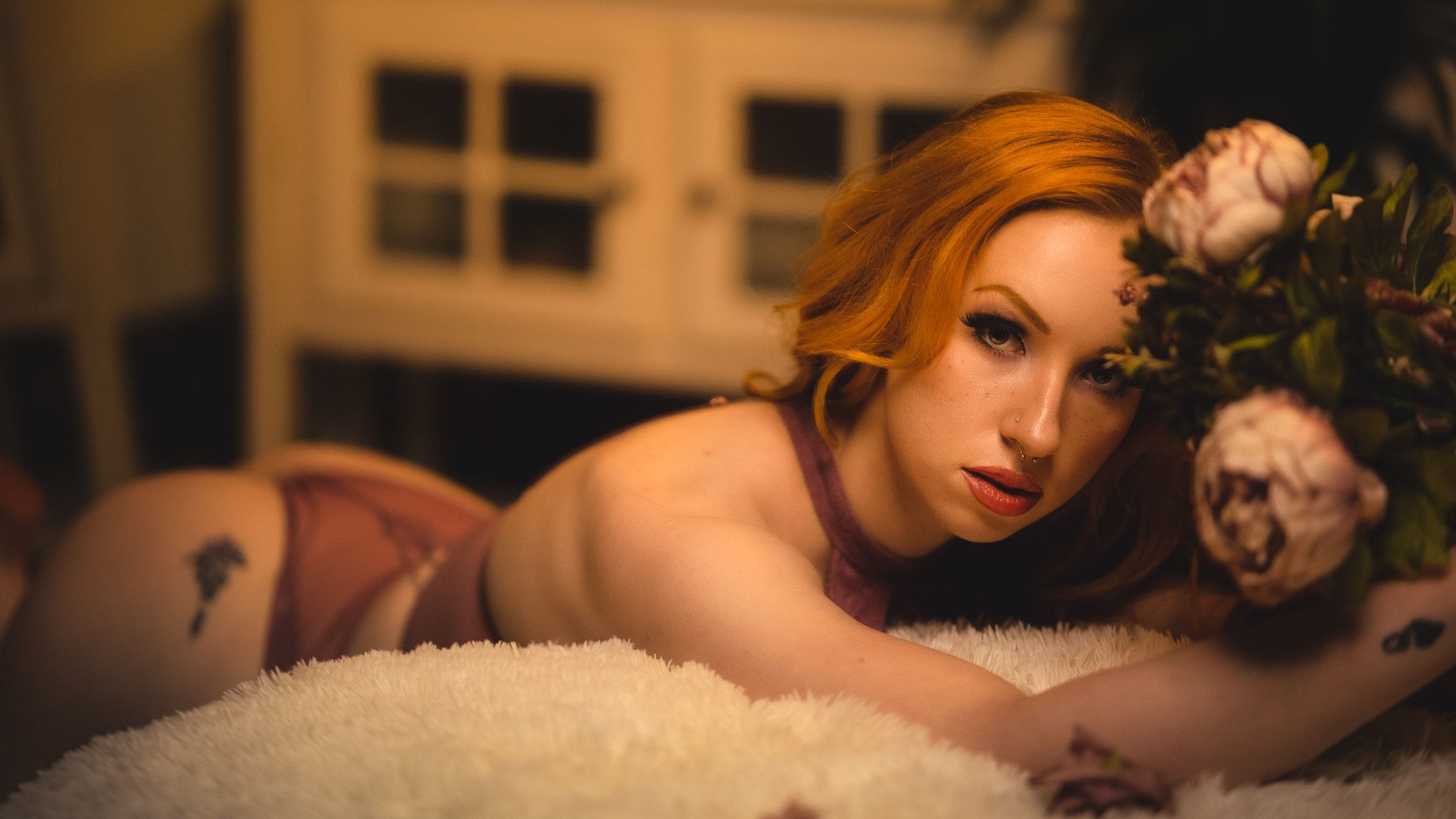 a sexy boudoir photo of redheaded model leaning on a bed with flowers by photographer yohance bailey based in binghamton new york  serving ithaca syracuse upstate new york.jpg