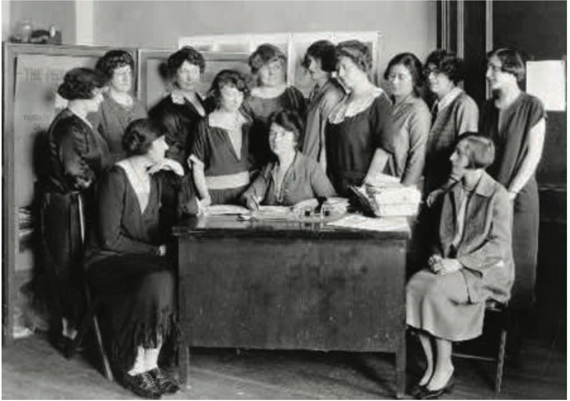 This historic 1920s photograph depicts birth control pioneer and activist Margaret Sanger seated at her desk. She is surrounded by staff members and supporters of the American Birth Control League, an organization she founded in 1921 to advocate for 