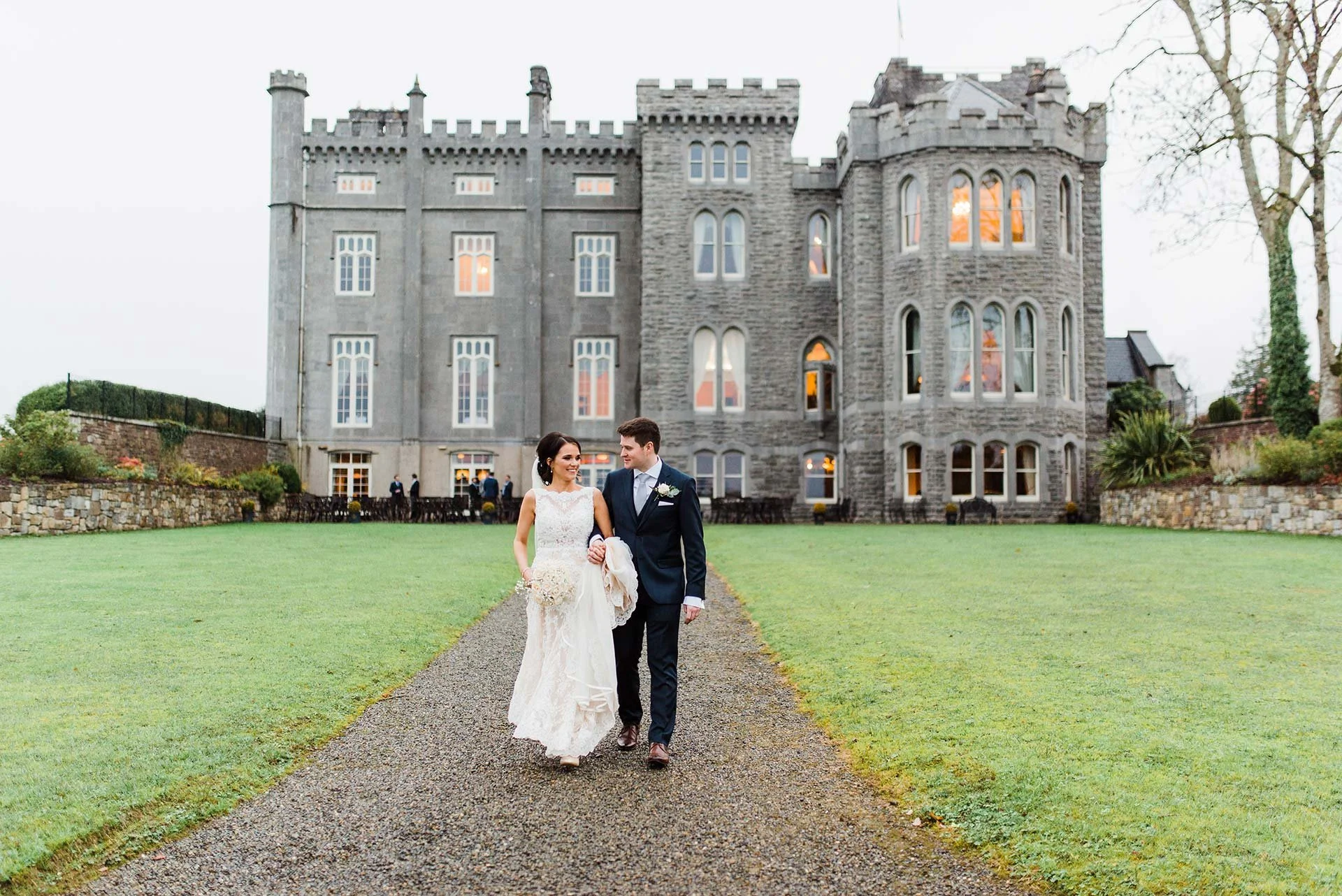 Bride and groom walking together outside a historic Irish castle wedding venue.