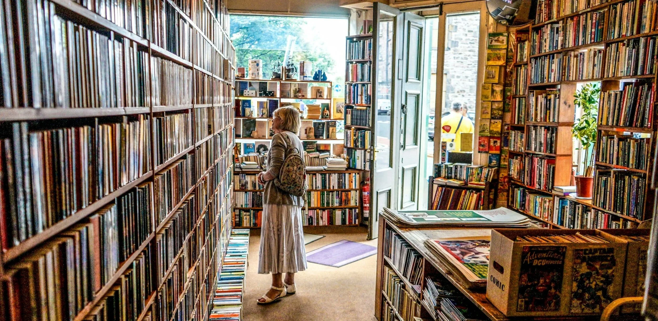 Customer browsing books in a cosy independent bookshop filled with wooden shelves and natural light.