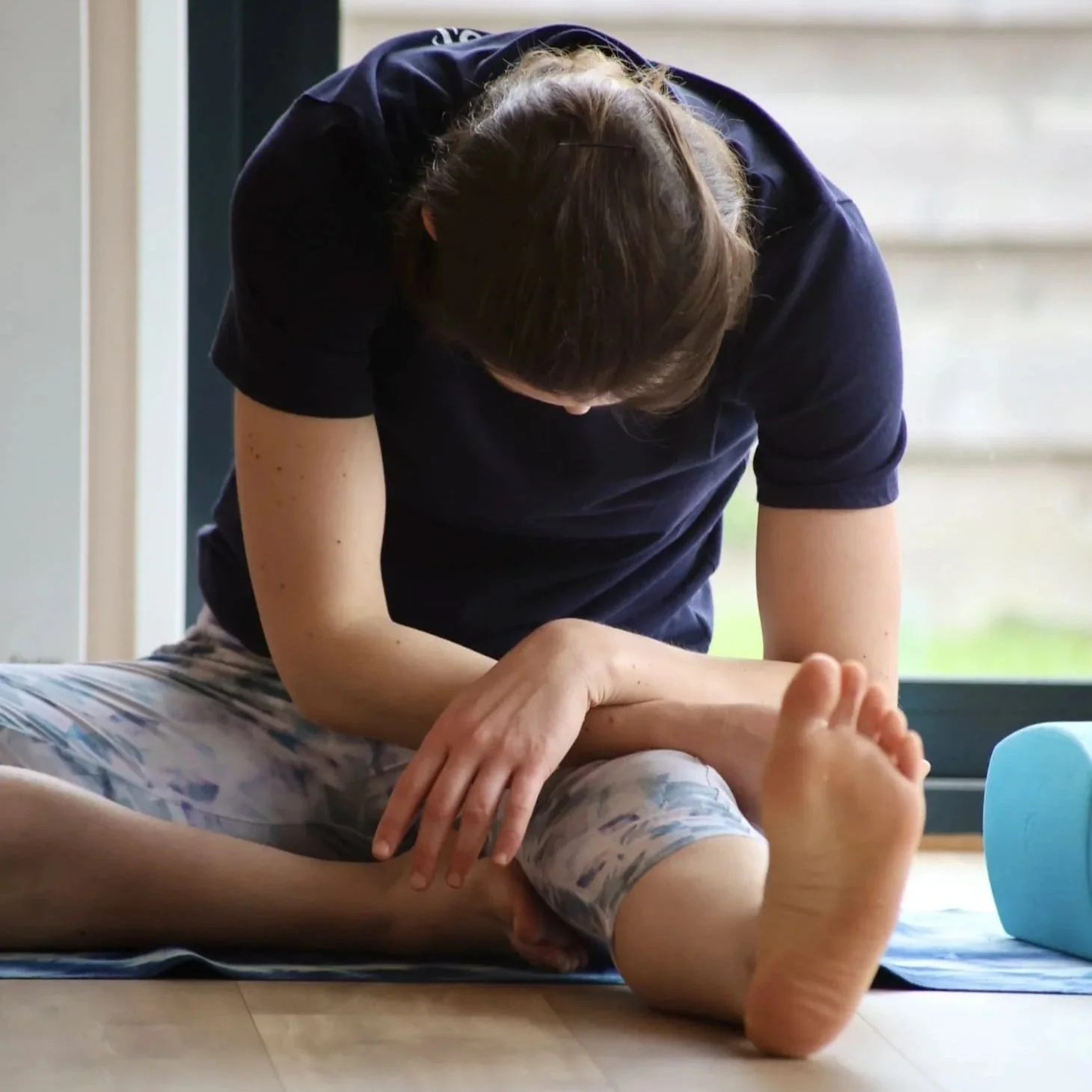 Une personne pratique l'étirement passif dans la posture de yoga du demi-papillon.