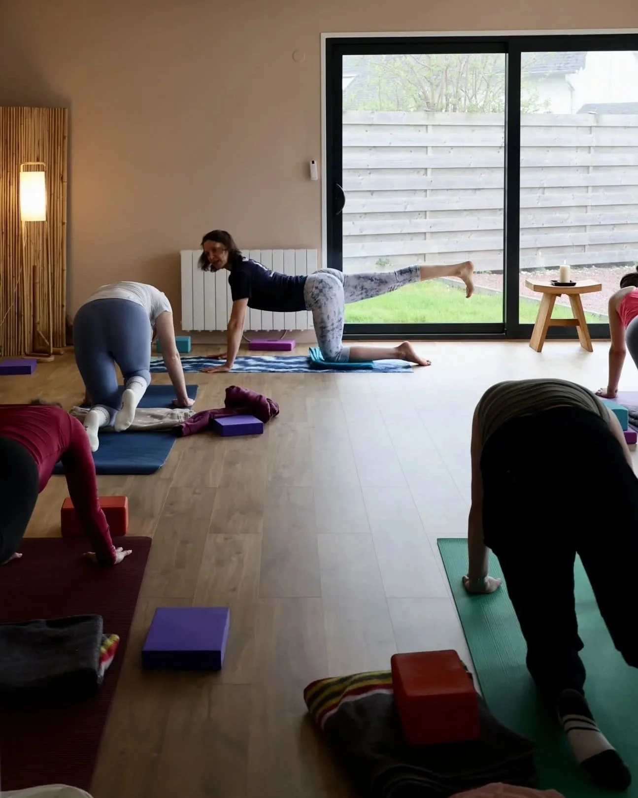 Groupe de personnes faisant une séance de yoga dans une pièce lumineuse.