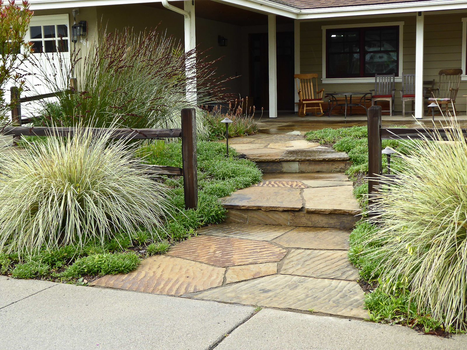 The front porch was expanded for seating and a simple split rail fence and gently stepped flagstone walkway welcome visitors and family.
