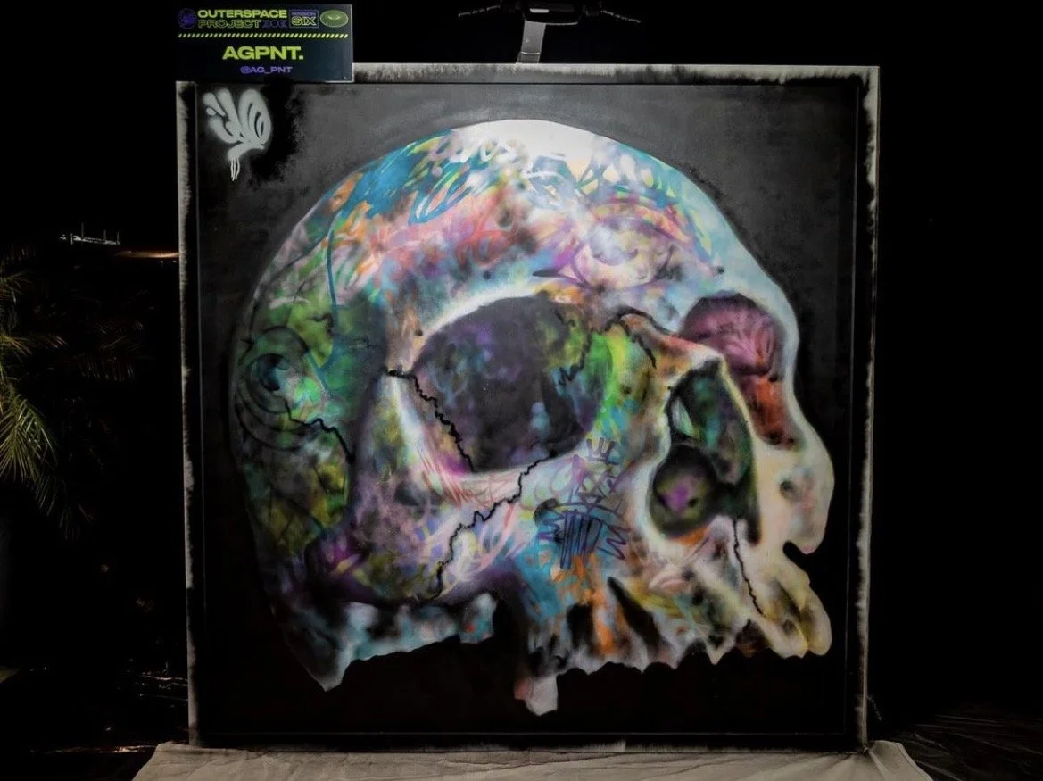 Colorful graffiti-style artwork of a human skull painted on a black background.