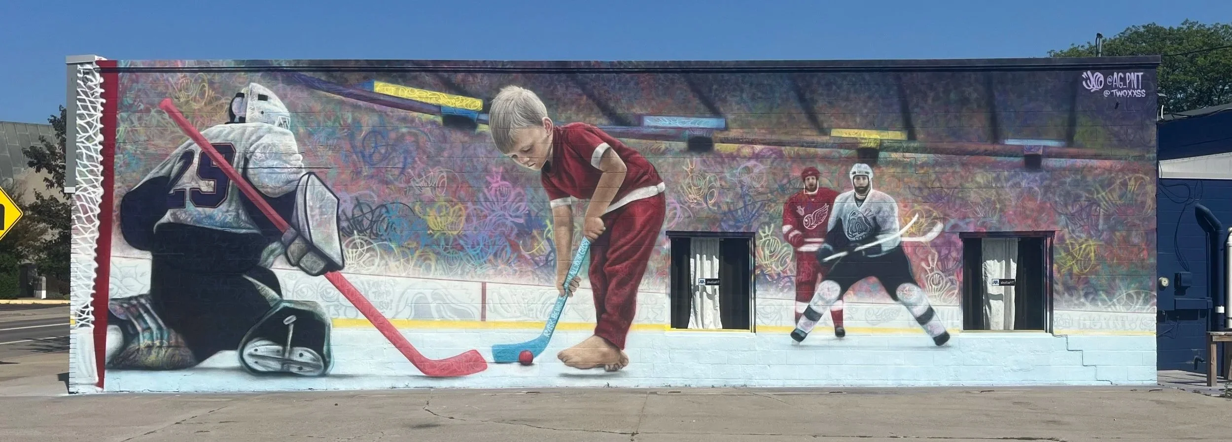 Colorful mural artwork depicting a young boy playing hockey, a hockey goalie, and two hockey players, with vibrant graffiti-style backgrounds.