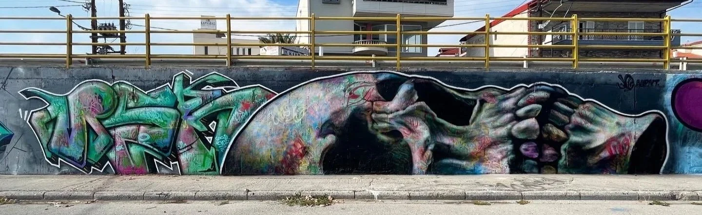 Colorful mural graffiti of a reclining human face and hands on an urban wall.