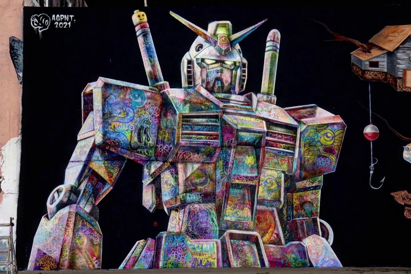 Colorful graffiti art of a robot resembling a Gundam with a helmet, glowing eyes, and wielding swords, on a black background with the text 'AGPNT 2021' in the upper left corner.
