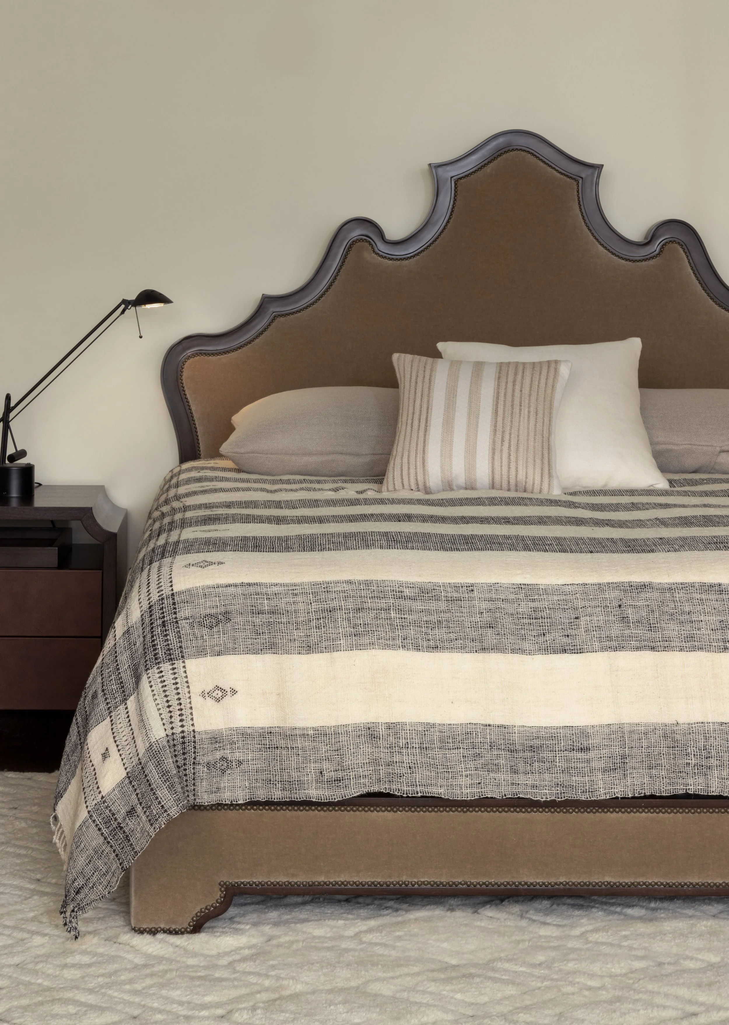 uhplstered headboard with stirped bedding and modern lamp.jpg
