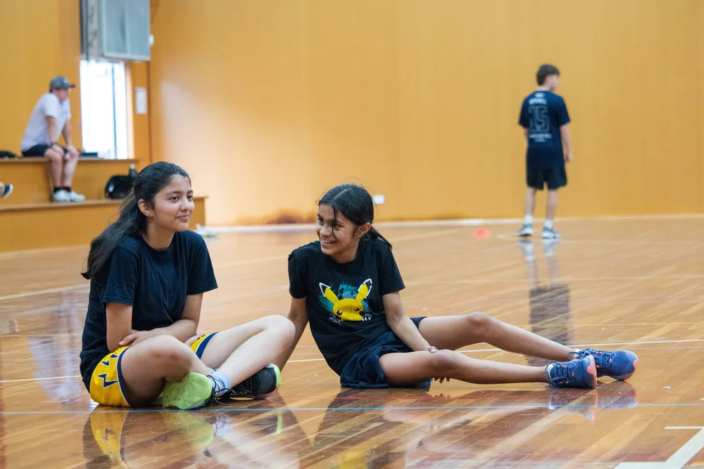 Two junior players laughing on court at training