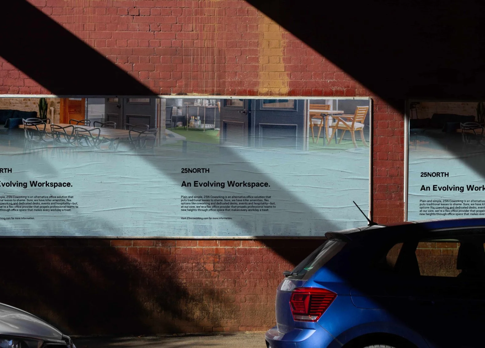 A large advertisement on a brick wall for 25NORTH coworking space, featuring images of indoor and outdoor seating areas, with text describing it as an evolving workspace.