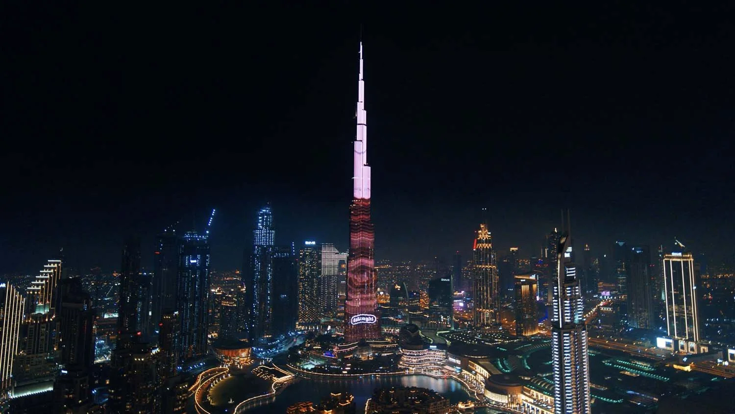 Drone view of the Burj Khalifa lit up by an LED brand projection above Downtown Dubai at night