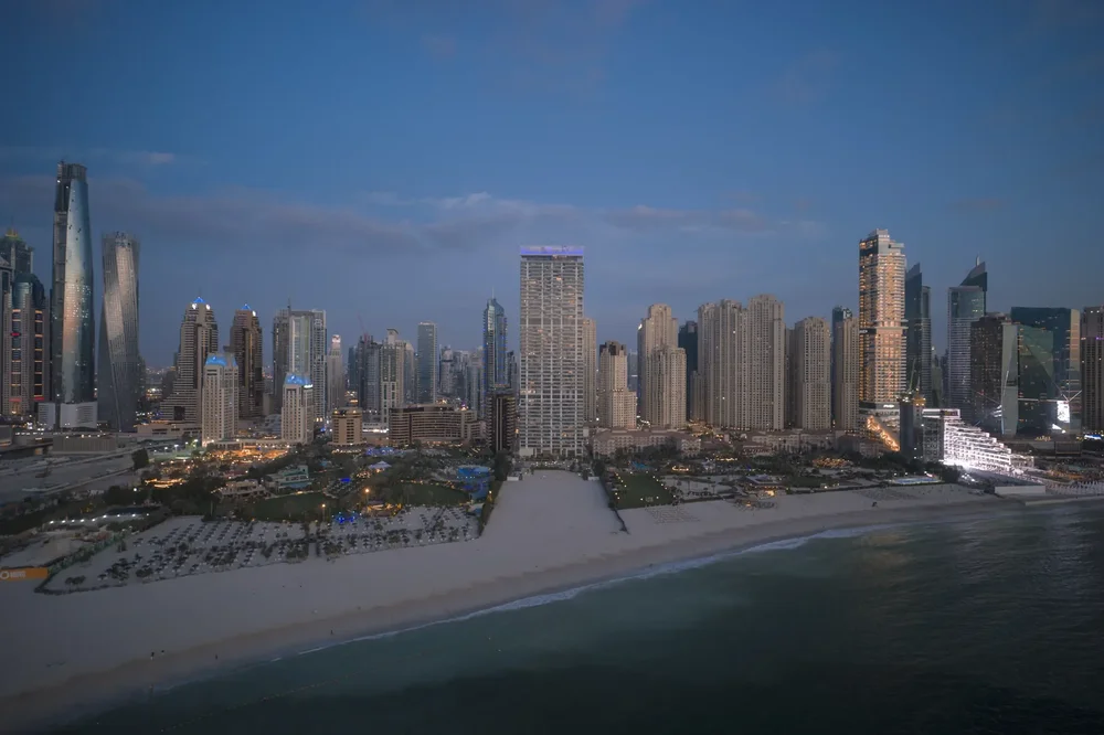 Wide aerial view of the Dubai Marina coastline, beach and skyscrapers at dusk