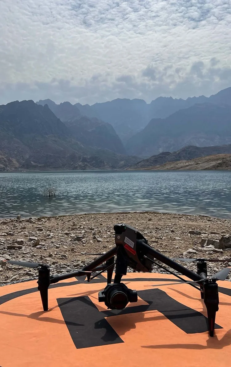 Inspire drone on a landing pad by a lake with mountains behind