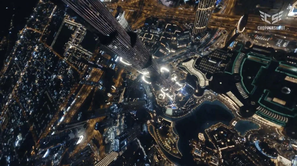 Drone view looking straight down the Burj Khalifa onto Downtown Dubai and the Dubai Fountain lake at night